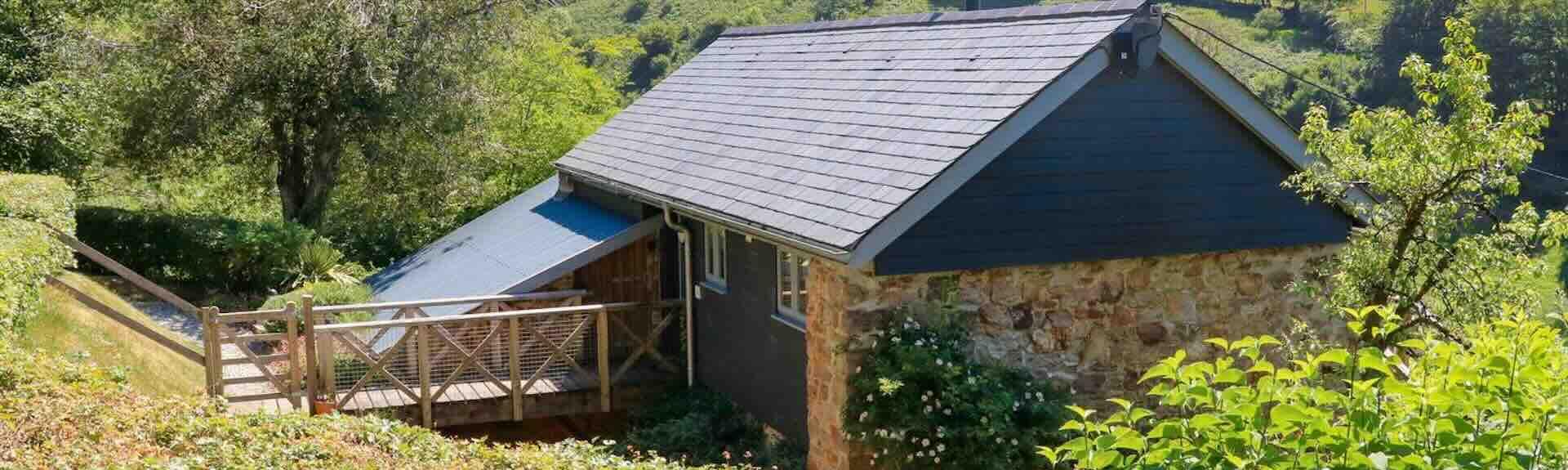 A single-storey, stone-built, luxury Exmoor barn conversion surrounded by trees and hedgerows.