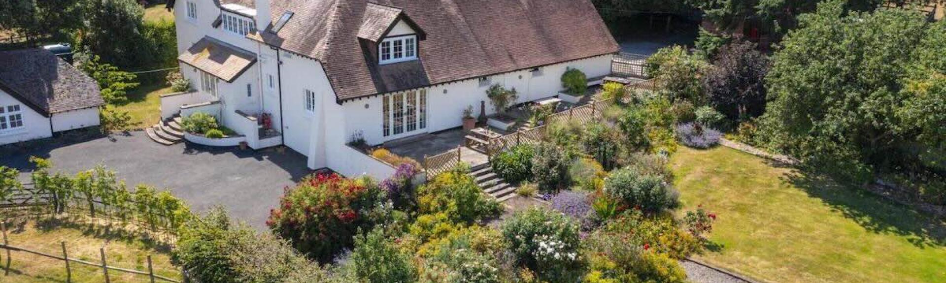 Aerial view of a large holiday cottage on the Somerset coast surrounded by gardens.