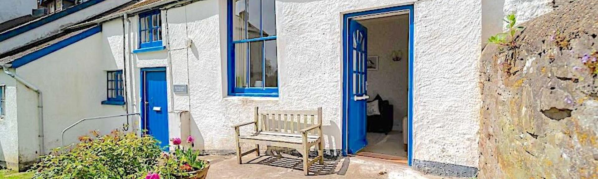 Exterior of a single-storey holiday cottage overlooking a courtyard.