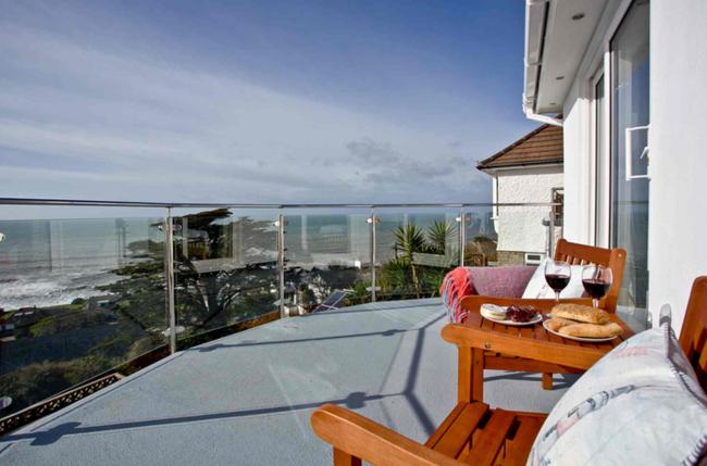 Outdoor  furniture on a glass-fronted balcony offers beach views on the Cornish coast at Downderry