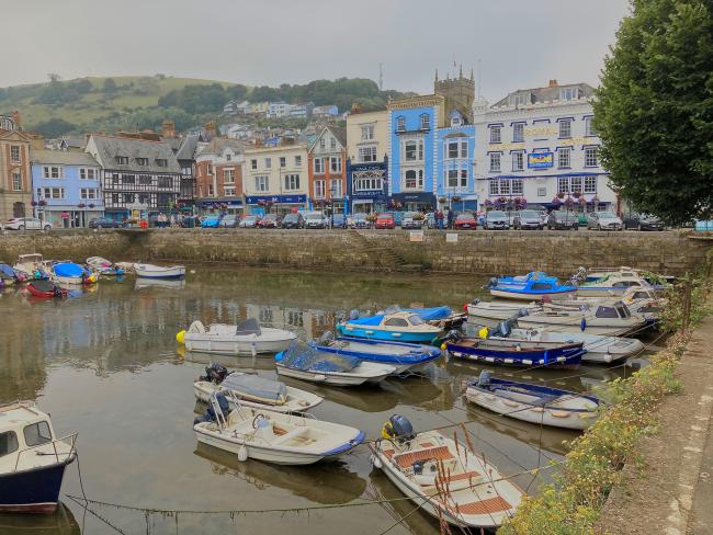 The Butterwalk at Dartmouth, a harbour at low tide filled with small pleasure boats and overlooked by shops an restaurants.