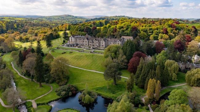 Aerial view of a large country house hotel in Devon surrounded by woods and fields on the edge of Datrmoor.