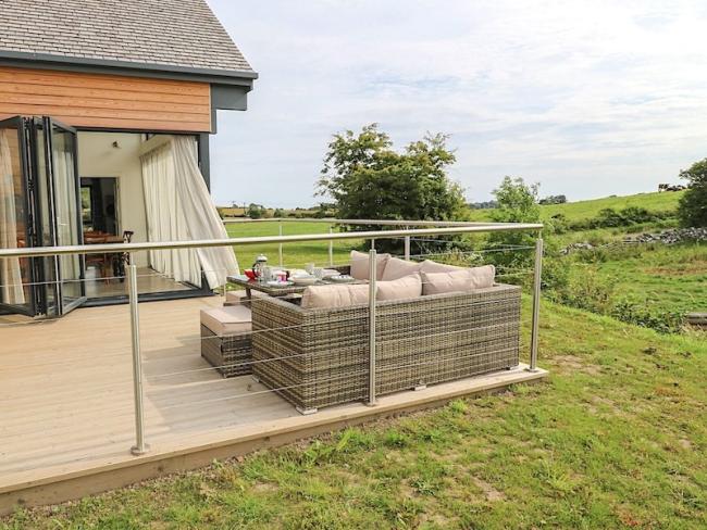 Outdoor seating on a wooden deck of an eco-lodge with bi-fold windows