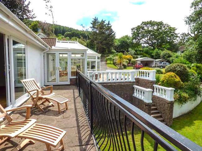 sun loungers on a terrace overlook a large well-maintained garden in Abergavenny.