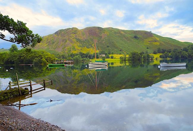 Mountains are reflected in the still water in a bend on the River Eden.