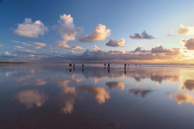 Small clouds are reflected in the wet surface of a sandy beach in North Devon.