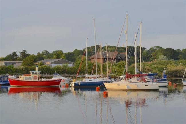 Small craft moored in mid stream in a Hampshire river at sunset.