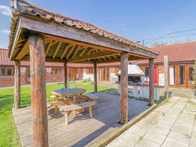 A covered bbq area in a garden of a barn conversion.