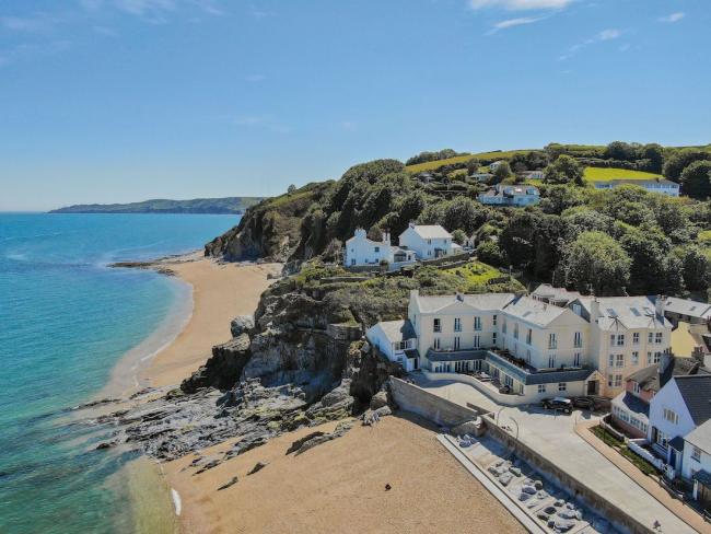 Cottages on a promenade look over a sandy South Devon beach.