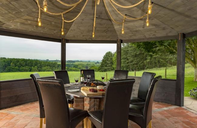 A table for eight beneath a pergola with far-reaching rural views.