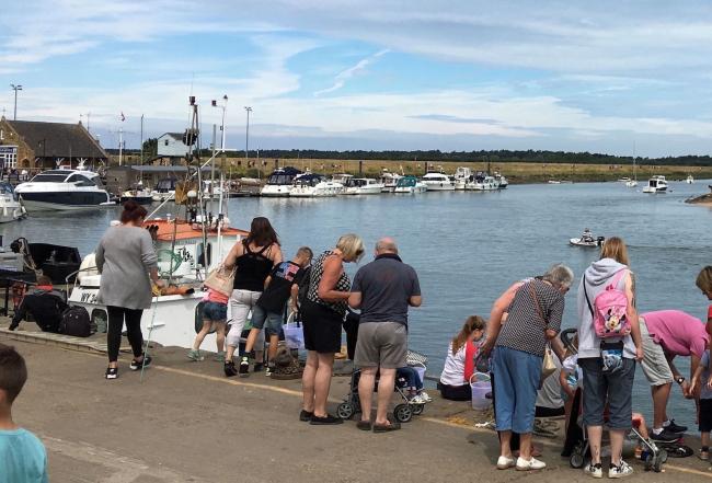 Families crabbing on a quayside at high tide