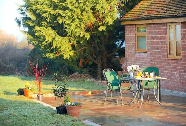 A table for two laid for tea on a cottage courtyard.