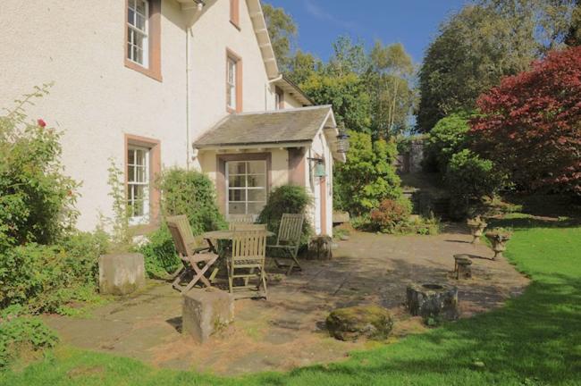 The Victorian Cottage with a covered porch overlooks a lawn and terrace.