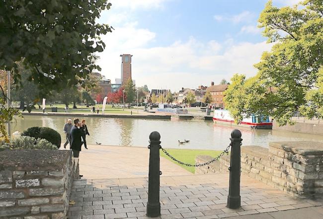 Riverside view with waterside gardens, moored barges and a theatre