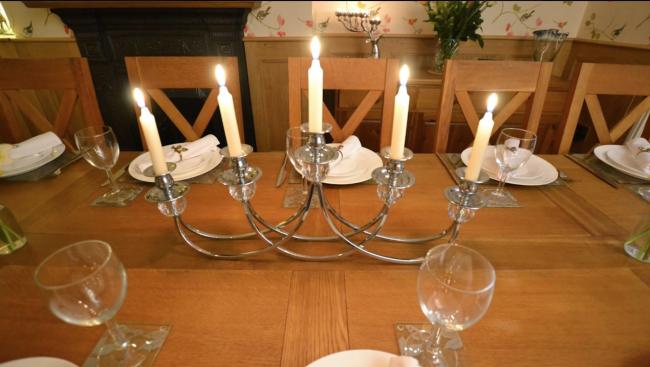 5 brightly burning candles on a table candelabra.