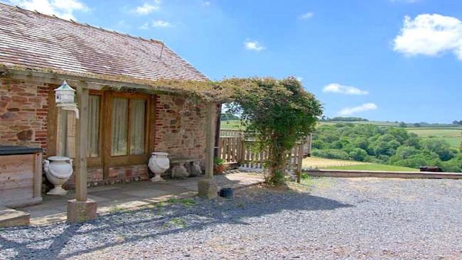 A single-storey barn conversion with a vine-clad pergola.