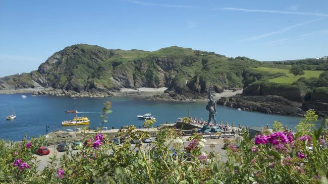 Panoramic view of the entrance to Ilfracombe Harbour, guarded by a giant statue of a woman waving a sword.