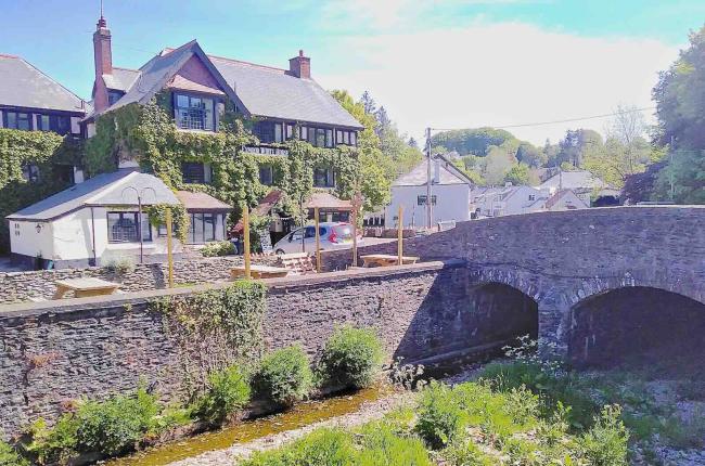 Exterior of a riverside pub next to a stone bridge.