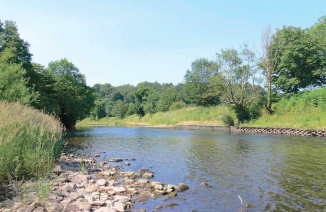 The wide, shallow River Usk flows between tree-lined banks in the Monmouthshire countryside.