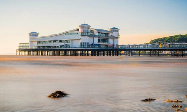 A North Somerset seaside pier spans a sandy beach at low tide.