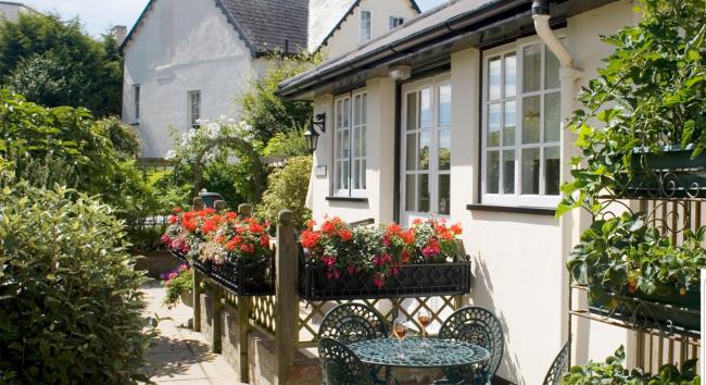 A conservatory overlooks a flower-filled garden.